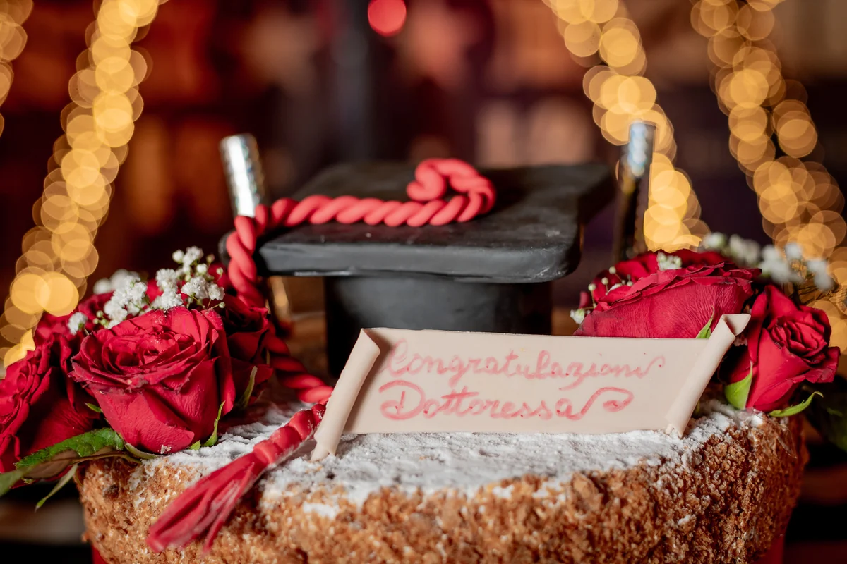 Torta di laurea con rose rosse e la scritta Congratulazioni Dottoressa
